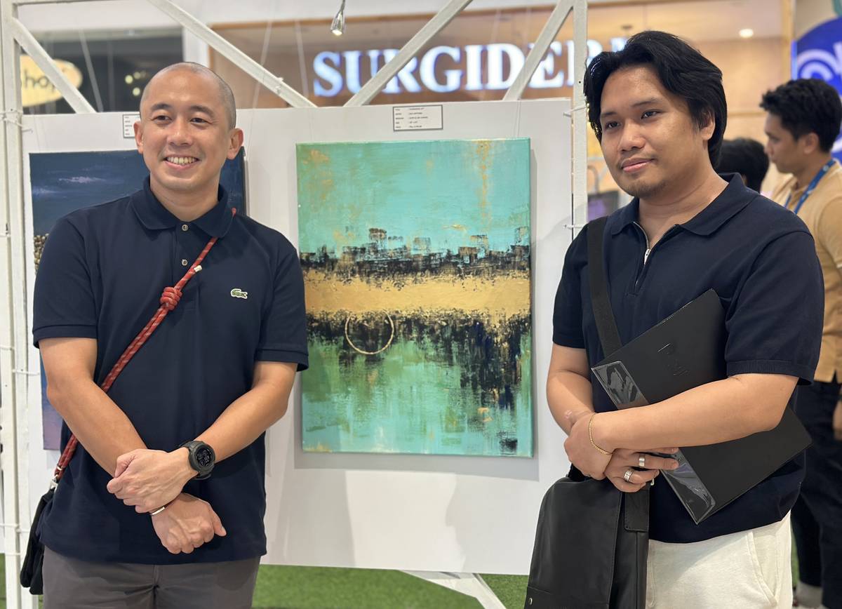 SM Supermalls’ regional operations manager Jesse Herrera (left) with artist Jose Antonio Japitana and his artwork.